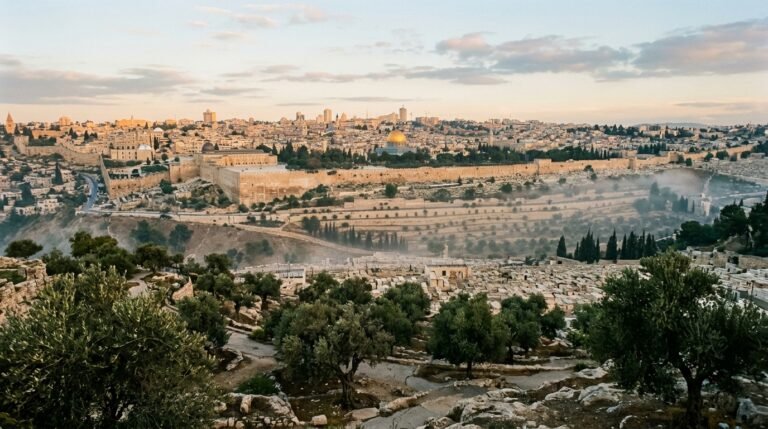 Panorama histórico de Jerusalém ao amanhecer com as antigas muralhas de pedra e oliveiras do Monte das Oliveiras sob névoa dourada